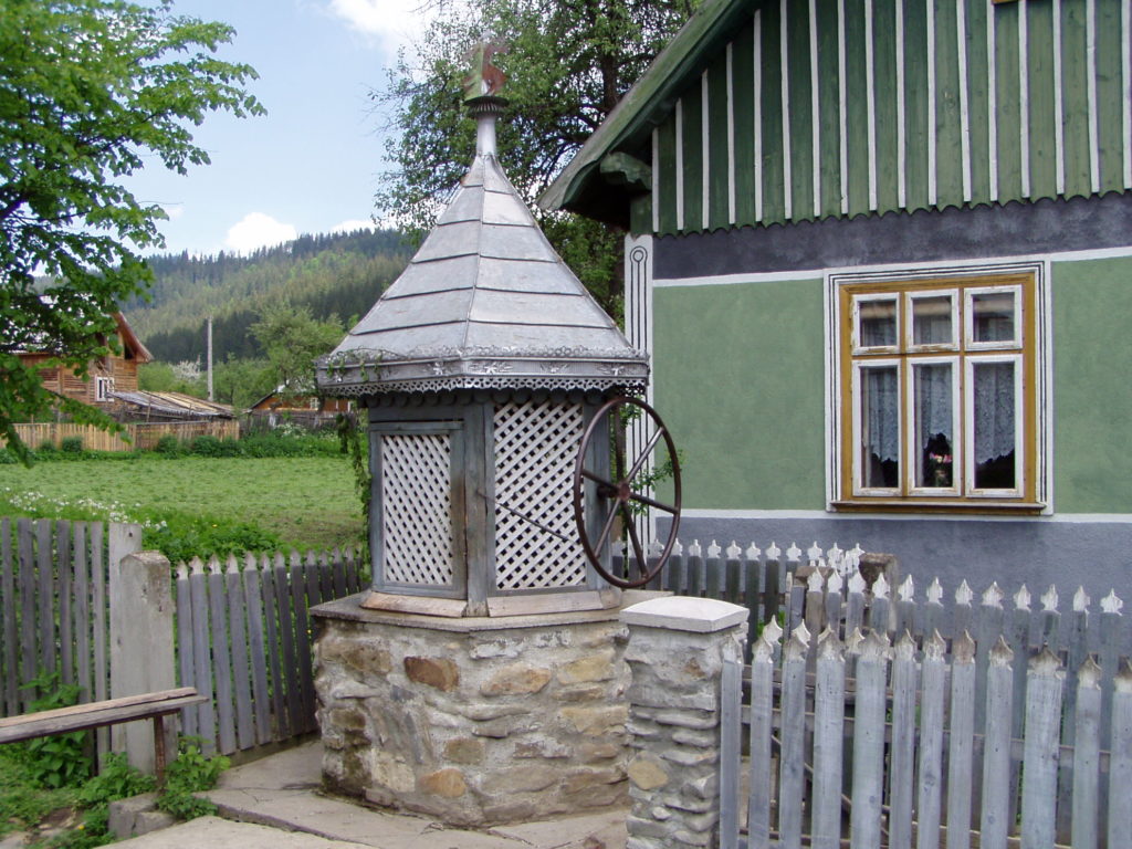 Typischer Brunnen nebst altem Bauernhaus in der Bukowina